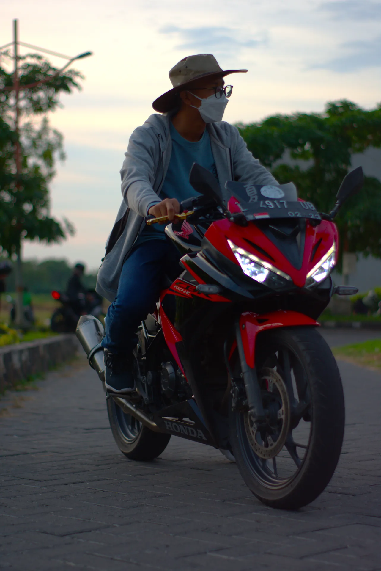 Rider wearing a hat and face covering travelling on a red CBR motorcycle