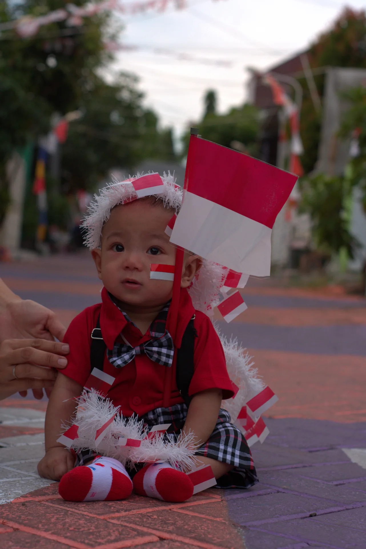 Close portrait of Azel in a red outfit beside an Indonesian flag