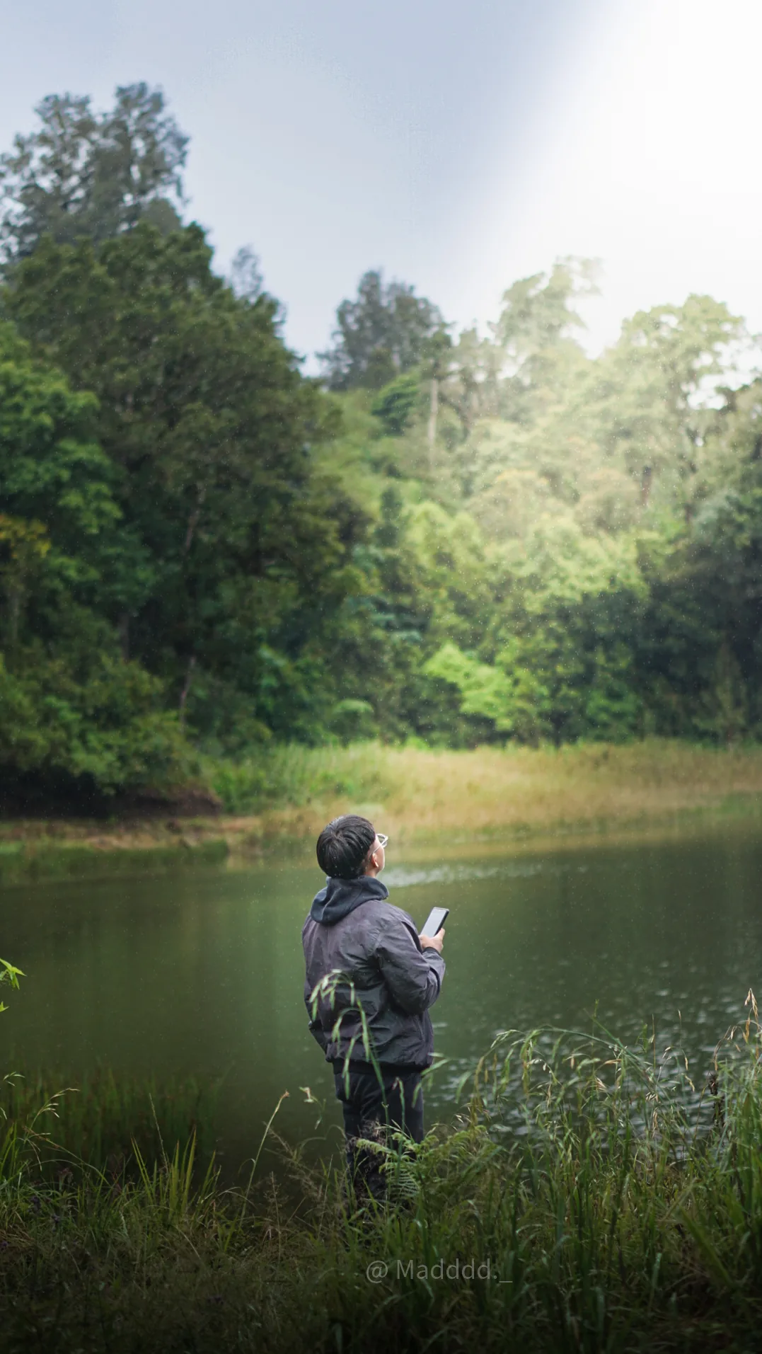 A visitor facing the calm water and dense forest at Ranu Regulo