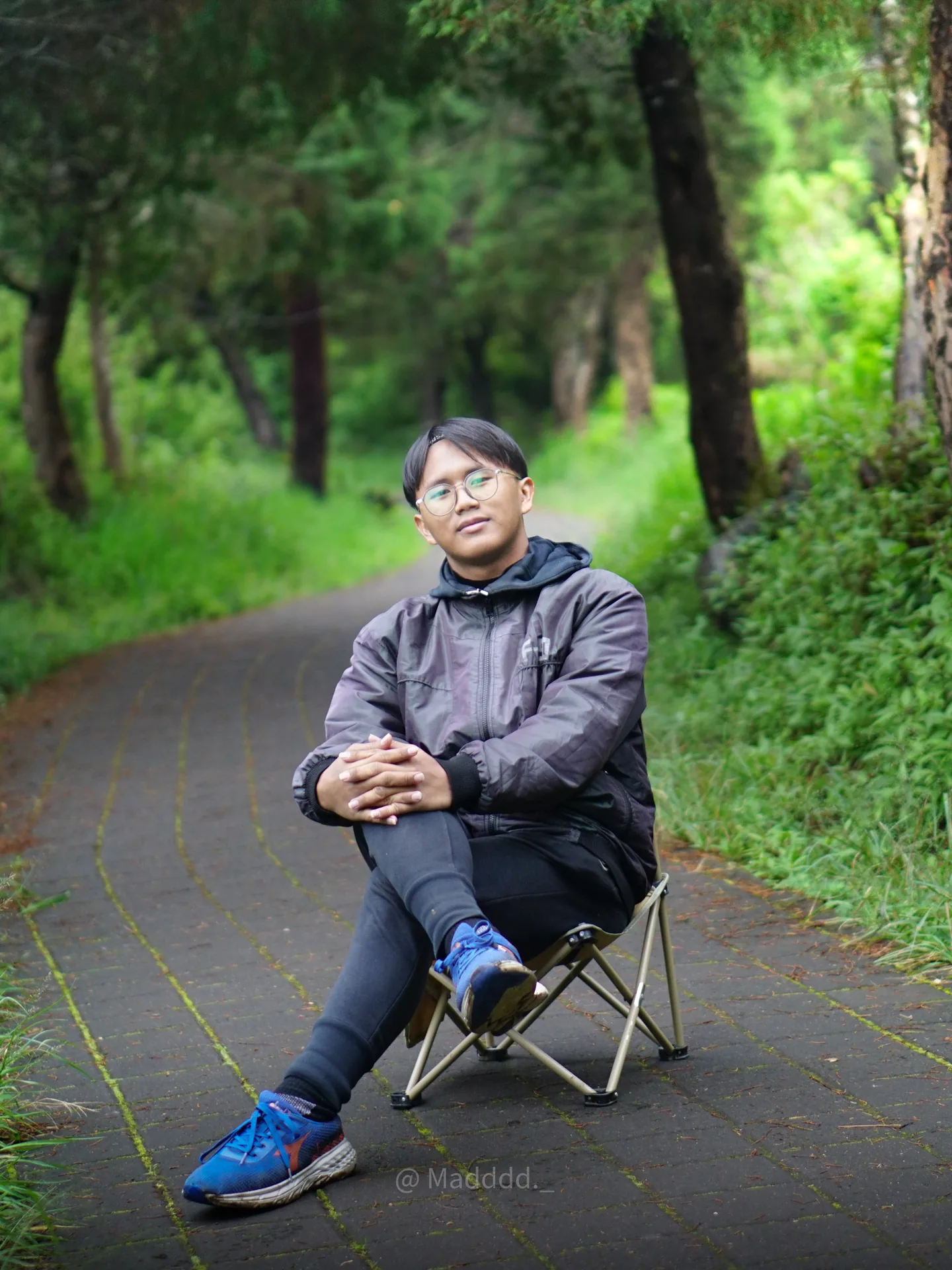 Portrait of Ahmad Farrel seated beside a green forest road near Ranu Regulo